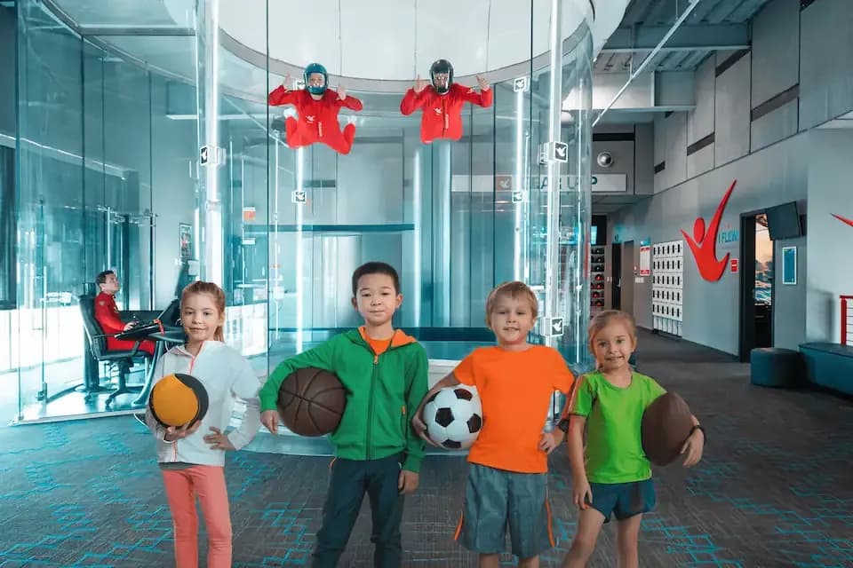 kids in front of flight tunnel while instructors are flying
