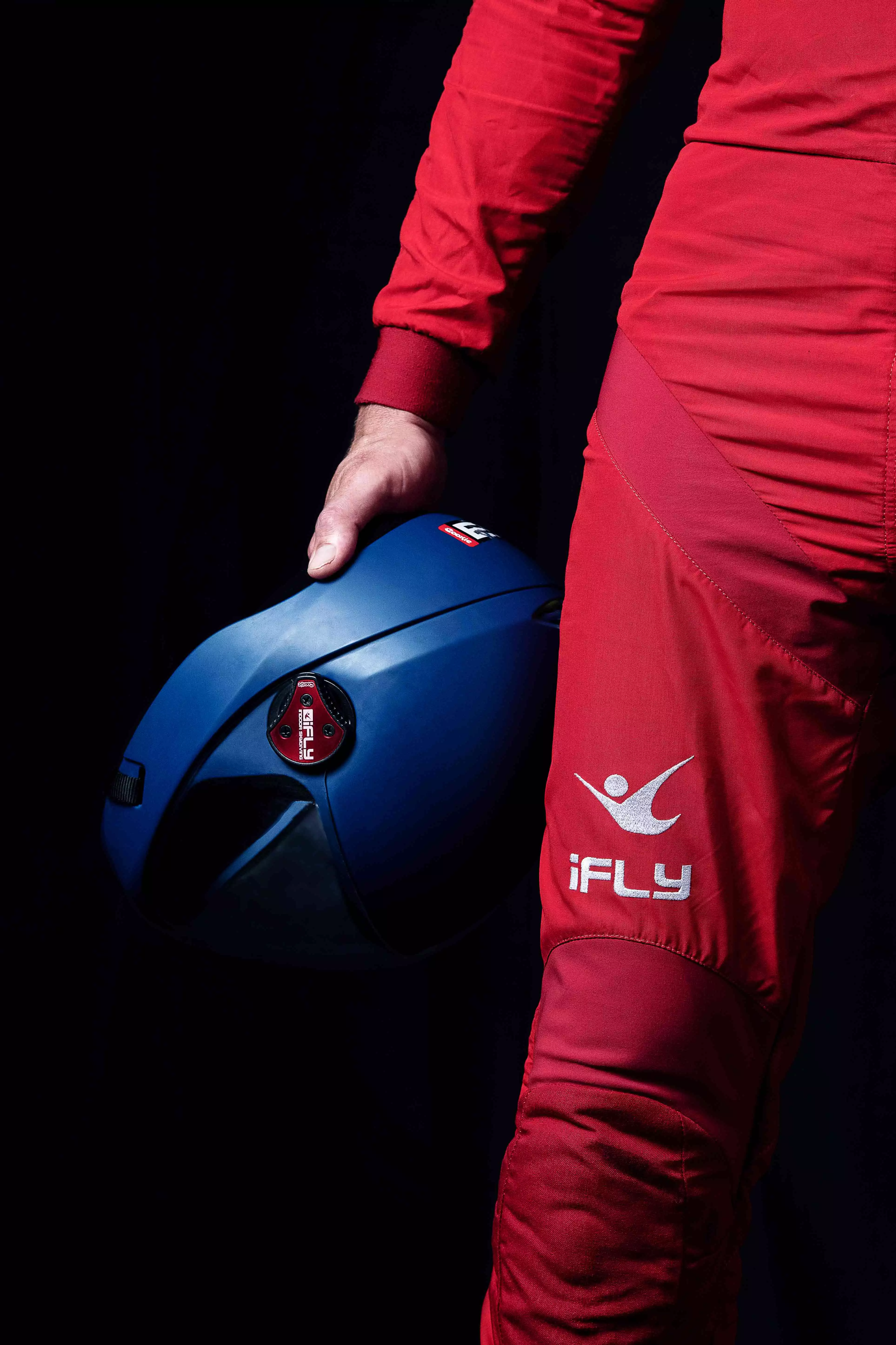 Skydiving adult in a red iFLY skydiving suit holding a blue helmet