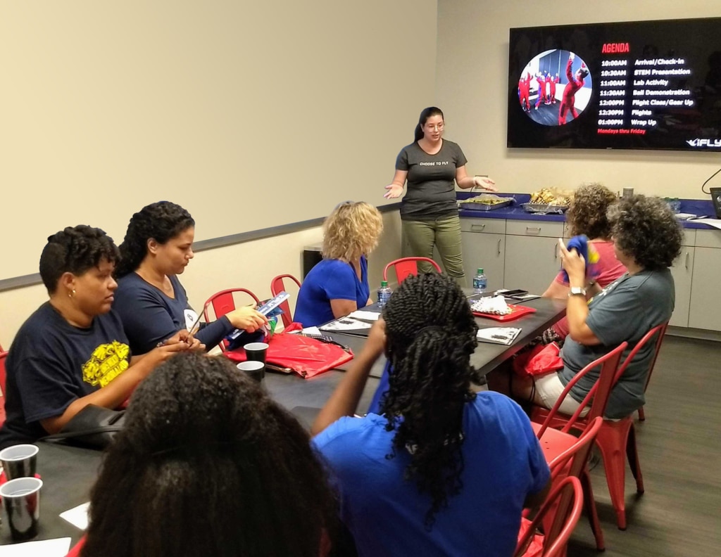 Female instructor teaching a group of students how to indoor skydive in a classroom at iFLY